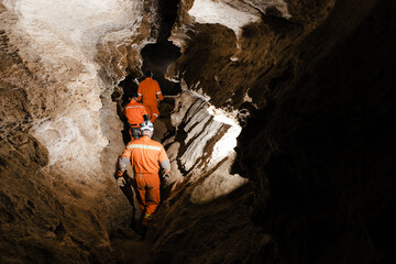 Three men, strong physique, explore the cave. Men dressed in special clothes to pass through the...