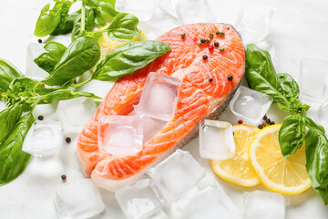 Raw salmon steak, lemon and ice cubes on light background