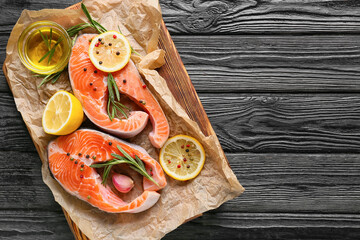 Raw salmon steaks, lemon and spices on dark wooden background