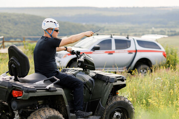 The rescuer, a beautiful athletic physique, rides an ATV in the middle of the field © nazariykarkhut
