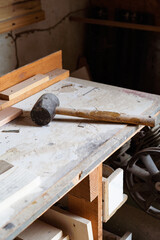 A rubber hammer  with wooden grip on the carpenter's table at the workshop.