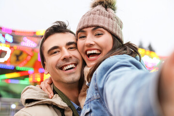 Happy young couple taking selfie in amusement park on Christmas eve