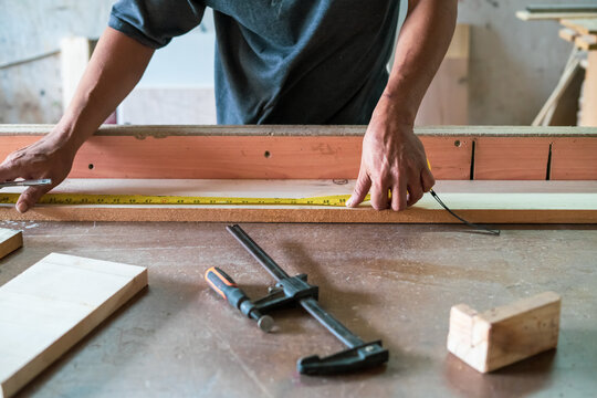 Carpenter measuring the wood at the workshop.