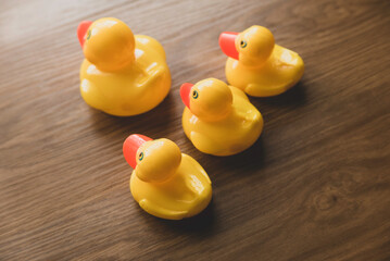 Concept of leader and follower. Selective focus of a small toy duck follow a big duck on wooden background.