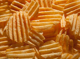 Background of fried potato chips with paprika. Relief potato chips closeup.