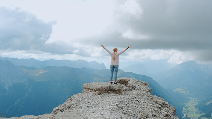 Young woman with outstretched arms enjoying the beauty of nature on mountain rock. Fantastic landscape view.