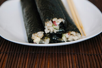 Home rolls. Rice and fish wrapped in nori seaweed on a white plate.