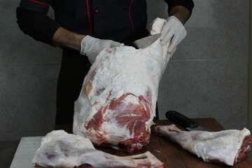 A butcher wrapping a piece of pork meat on a counter