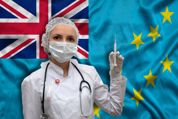 Young woman doctor in medical uniform on the background of the national flag of Tuvalu is holding a...