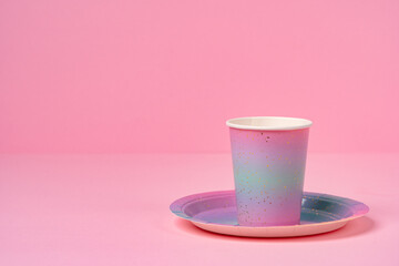Pink disposable cup and plate on pink background
