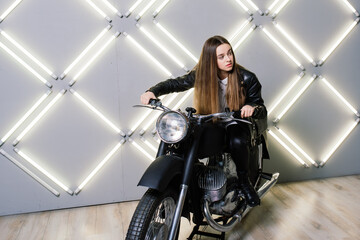 Fototapeta na wymiar Young fashion girl posing in black leather with motorcycle.
