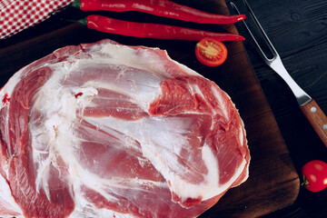 Raw lamb leg on dark wooden board