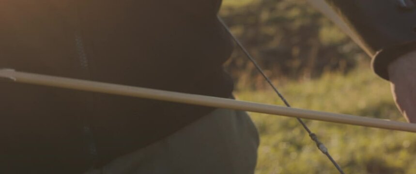 Archer man take arrow nock attach on bow pull aim shoot closeup flare