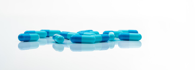 Blue antibiotic capsule pills spread on white background. Antibiotic drug resistance. Pharmaceutical industry. Healthcare and medicine concept. Health budget concept. Capsule manufacturing industry.