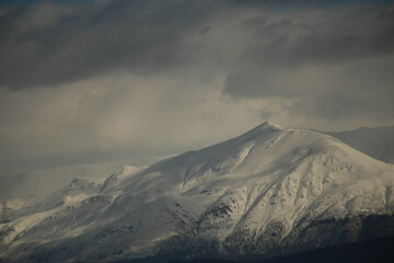 Fototapeta na wymiar mountain pick with snow on top clouds ice winter background in mitsikeli mountain grreece