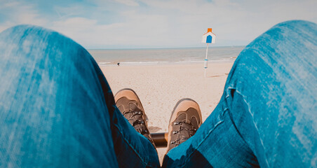 Closeup of a person wearing blue jeans while laying at the beach during the daytime - Powered by Adobe