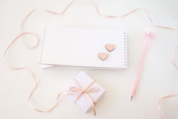 Note paper with heart, gift box with ribbon and pen on white delicate background. Happy Valentine's Day