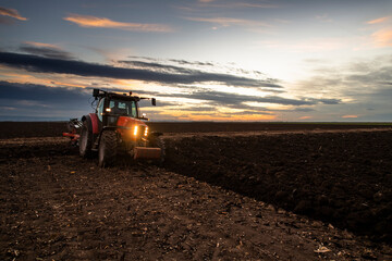 Obraz premium Tractor on the field during sunset.