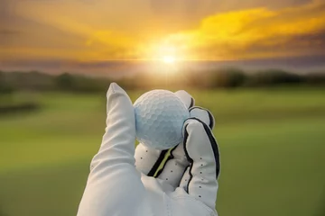 Schilderijen op glas golfer weergegeven: golfbal bij de hand houden met groen gras golfbaan zonlicht stralen achtergrond zonlicht. © APstudio