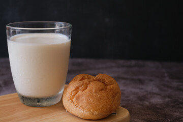 Homemade choux cream or Choux Pastry or Profiterole or Eclair or cream puff and a glass of milk on wooden plate with dark background. French dessert. selected focus. 