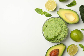 Bowl of guacamole, avocado, lime and basil on white background, space for text