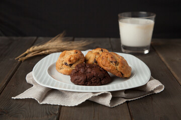 Cookies on a wooden table with a glass of milk and wheat ear