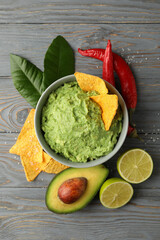 Concept of tasty eating with bowl of guacamole on wooden background, top view