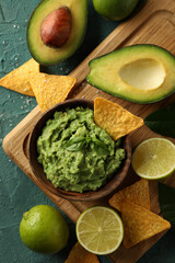 Concept of tasty eating with bowl of guacamole on green textured background