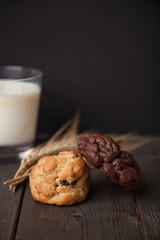 Cookies on a wooden table with a glass of milk and wheat ear