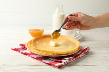 Female hand pour jam on crepe rolls on white wooden table