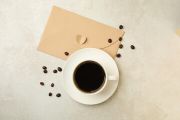Coffee beans, cup of coffee and envelope on textured background