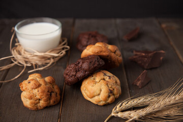 Cookies on a wooden table with a glass of milk and wheat ear