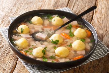 Traditional Liechtenstein soup with ham, vegetables and cornmeal dumplings close-up in a plate on the table. horizontal