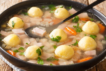 Delicious Liechtenstein cuisine soup with ham and cornmeal dumplings close-up in a plate on the table. horizontal