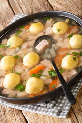 Hafalaab Traditional Liechtenstein soup with ham and cornmeal dumplings closeup in the plate on the table. vertical