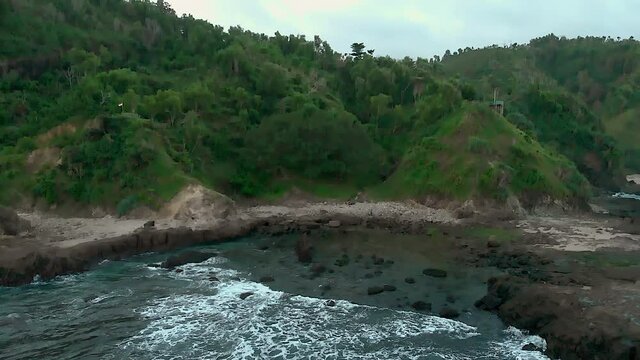 Aerial landscape view of Watulumbung rock beach with green trees at rock cliff