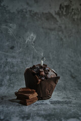 chocolate muffins on a dark background with an extinguished candle