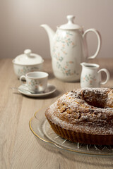 Bundt cake with powdered sugar. Porcelain in the background.