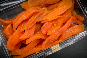 Dried mango on a in a plastic box on dark background. Selective focus.