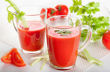 Fresh tomato juice with celery and parsley in a glass on a white table. Vitamins, natural, healthy drink for breakfast.
