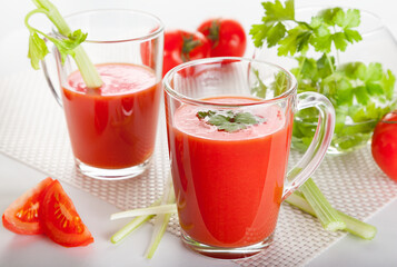 Fresh tomato juice with celery and parsley in a glass on a white table. Vitamins, natural, healthy drink for breakfast.