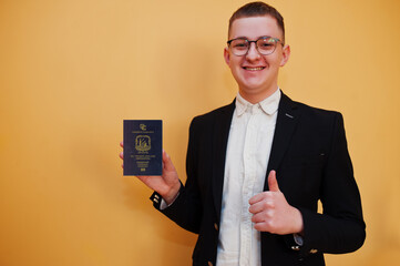 Young handsome man holding Saint Vincent and the Grenadines passport id over yellow background,...