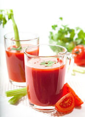 Fresh tomato juice with celery and parsley in a glass on a white table. Vitamins, natural, healthy drink for breakfast.