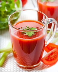 Fresh tomato juice with celery and parsley in a glass on a white table. Vitamins, natural, healthy drink for breakfast.