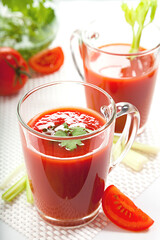 Fresh tomato juice with celery and parsley in a glass on a white table. Vitamins, natural, healthy drink for breakfast.