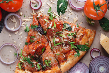 Slices Traditional Italian pepperoni pizza with tomatoes, grated metal cheese, onions and herbs, on a dark slate table with paper .