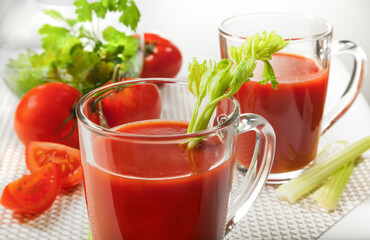 Fresh tomato juice with celery and parsley in a glass on a white table. Vitamins, natural, healthy drink for breakfast.