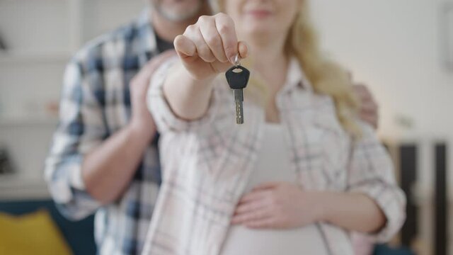 Expecting couple showing house key, affordable mortgage program, real estate