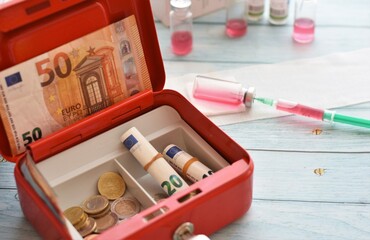 safe with euro money and a syringe with medicine in a sterile small bottles