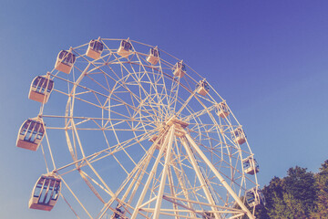 Vintage edit Ferris wheel on the background of the blue sky. Amusement park retro carnival, no...